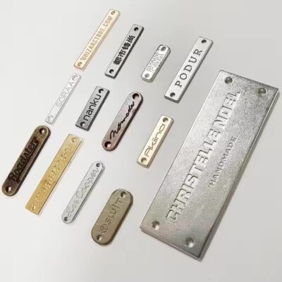 Close-up of custom-designed 3D engraved metal tags featuring detailed brand logos