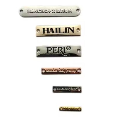Close-up of custom square-shaped metal tags engraved with letters for branding