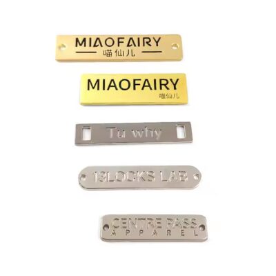 Close-up of custom square-shaped metal tags engraved with letters for branding