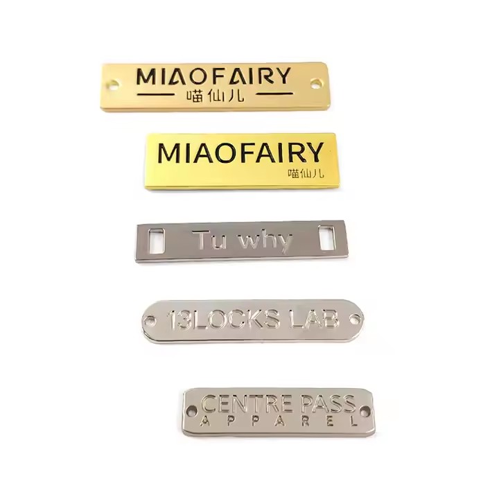 Close-up of custom square-shaped metal tags engraved with letters for branding